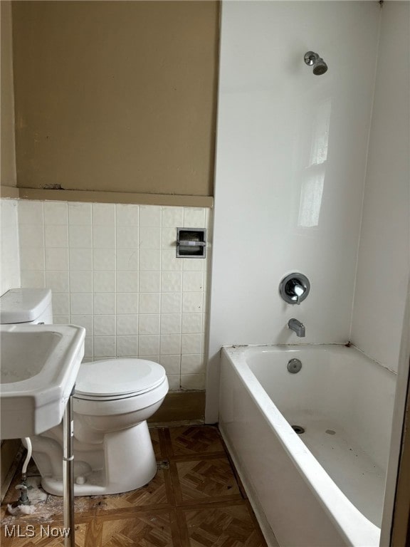 bathroom featuring tile walls, parquet flooring, and toilet