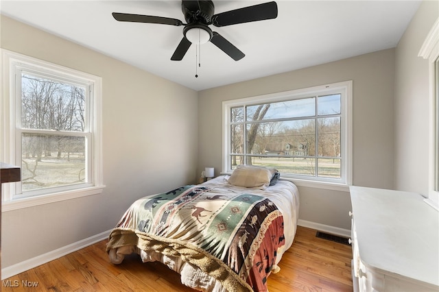 bedroom with light hardwood / wood-style floors, multiple windows, and ceiling fan