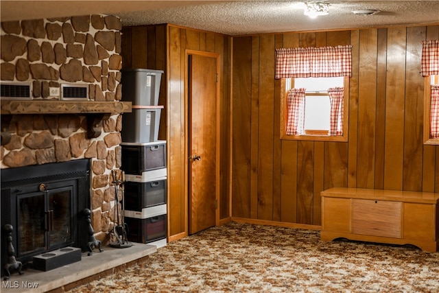 unfurnished living room with carpet floors, a textured ceiling, and wooden walls