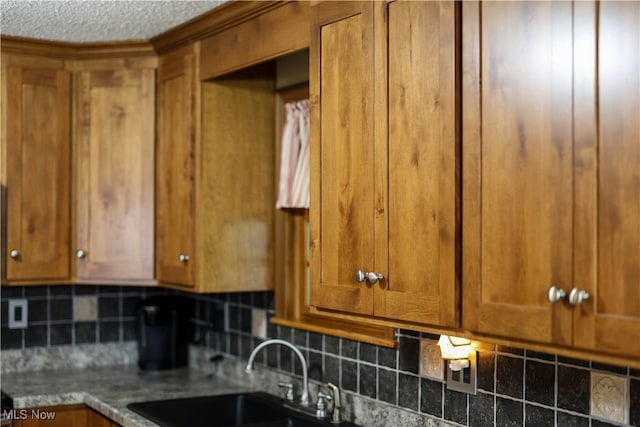 kitchen featuring tasteful backsplash, dark stone counters, and sink