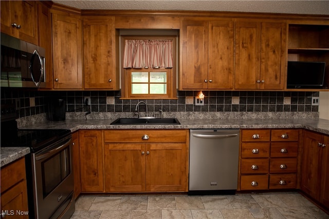 kitchen with backsplash, sink, dark stone counters, and appliances with stainless steel finishes