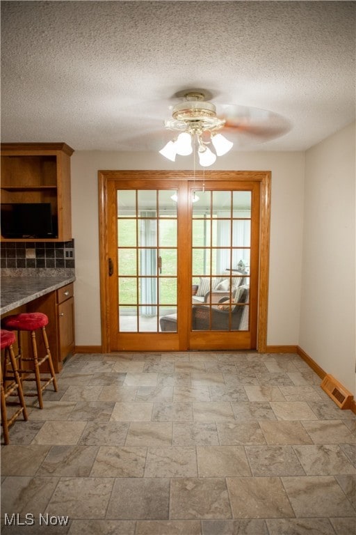 doorway to outside featuring ceiling fan and a textured ceiling