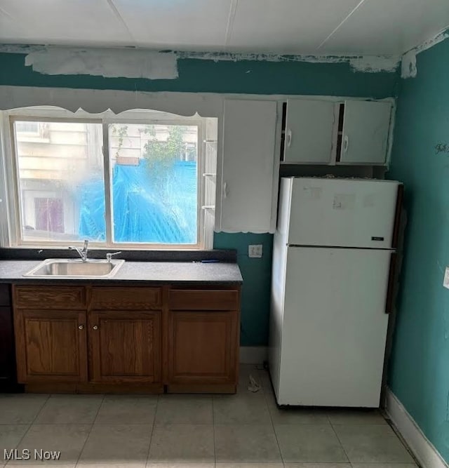 kitchen with white refrigerator, light tile patterned floors, and sink