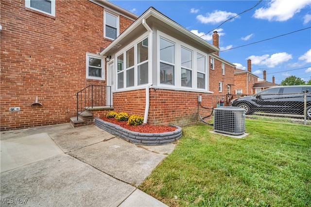 view of side of property with a lawn, cooling unit, and a patio area