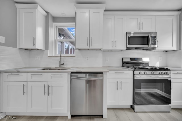 kitchen with white cabinets, light stone counters, appliances with stainless steel finishes, and sink