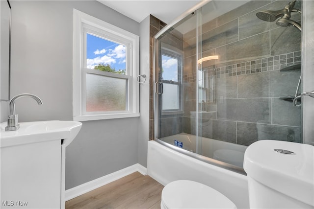 full bathroom with hardwood / wood-style floors, combined bath / shower with glass door, vanity, and toilet