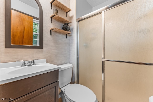 bathroom with walk in shower, vanity, and toilet