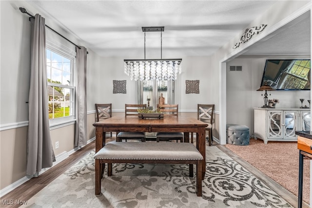 dining space featuring wood-type flooring and an inviting chandelier