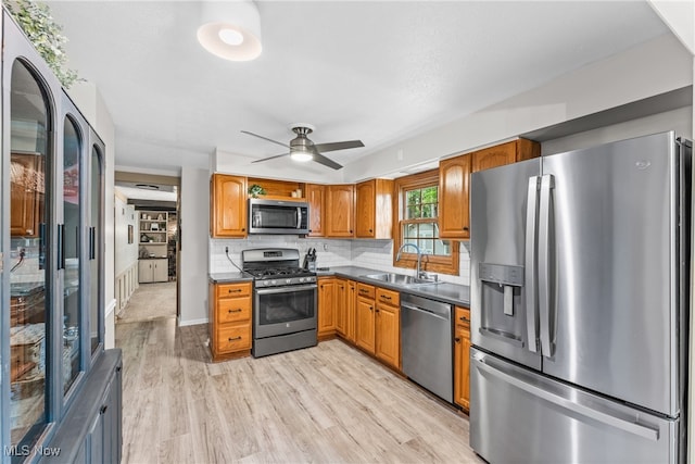 kitchen featuring ceiling fan, sink, tasteful backsplash, appliances with stainless steel finishes, and light hardwood / wood-style floors