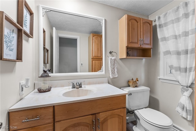 bathroom with a textured ceiling, vanity, and toilet