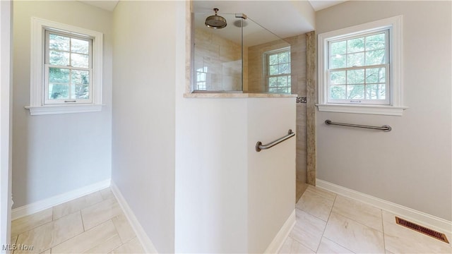 bathroom featuring tile patterned flooring, plenty of natural light, and tiled shower