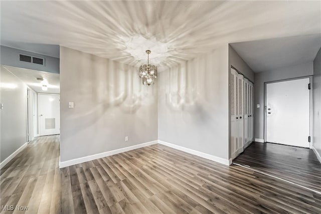 unfurnished room with dark hardwood / wood-style floors and an inviting chandelier