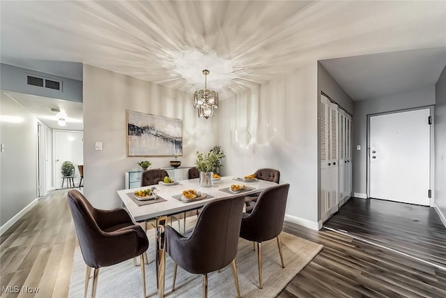 dining area with dark hardwood / wood-style floors and an inviting chandelier