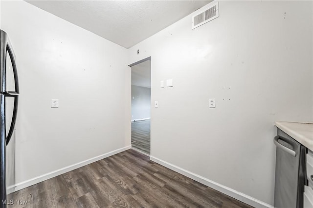 interior space with a textured ceiling, refrigerator, and dark wood-type flooring