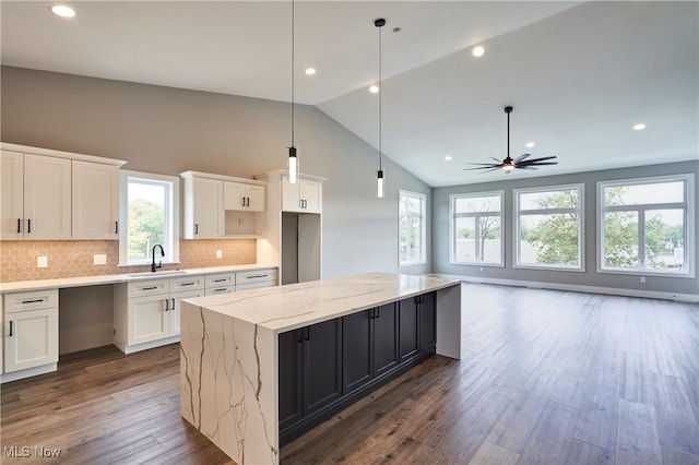 kitchen featuring pendant lighting, dark wood-type flooring, ceiling fan, a kitchen island, and white cabinetry