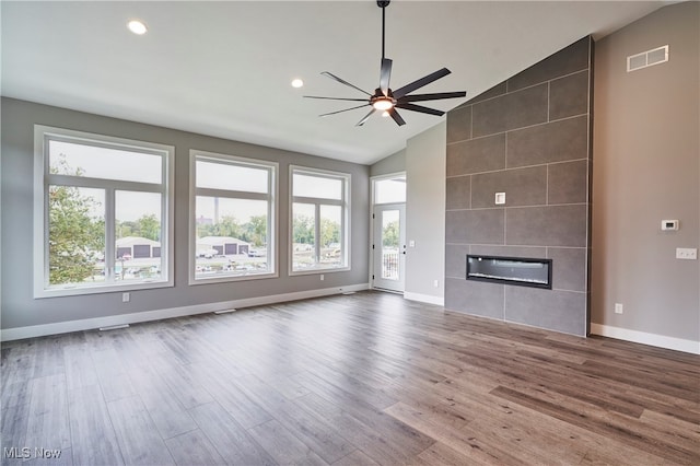 unfurnished living room featuring ceiling fan, a large fireplace, wood-type flooring, and a wealth of natural light