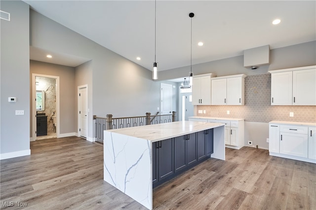 kitchen with white cabinets, a center island, light wood-type flooring, and pendant lighting