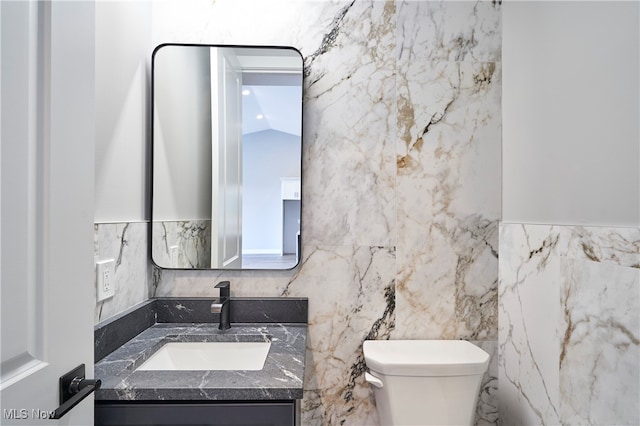 bathroom with vanity, toilet, lofted ceiling, and tile walls