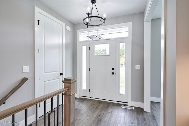 foyer entrance with hardwood / wood-style flooring and an inviting chandelier