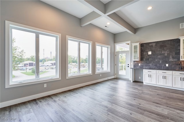 kitchen featuring beam ceiling, white cabinetry, tasteful backsplash, and light wood-type flooring