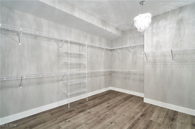 spacious closet with a notable chandelier and hardwood / wood-style flooring