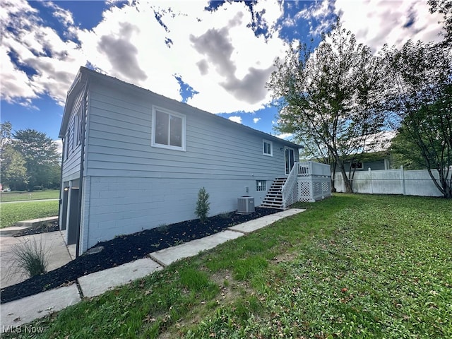 view of side of property with a lawn and cooling unit