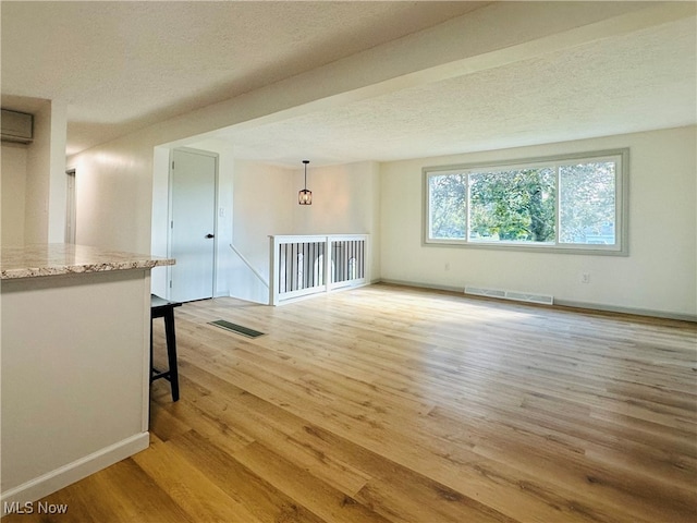 unfurnished room featuring light hardwood / wood-style floors and a textured ceiling