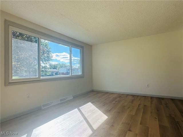 unfurnished room featuring wood-type flooring and a textured ceiling