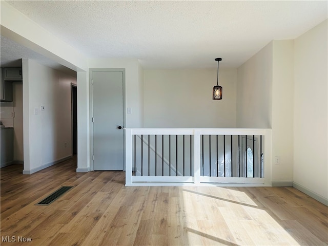 empty room with a textured ceiling and wood-type flooring