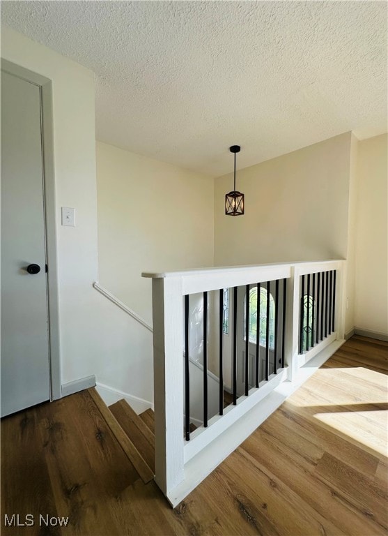 stairway featuring a textured ceiling and hardwood / wood-style floors