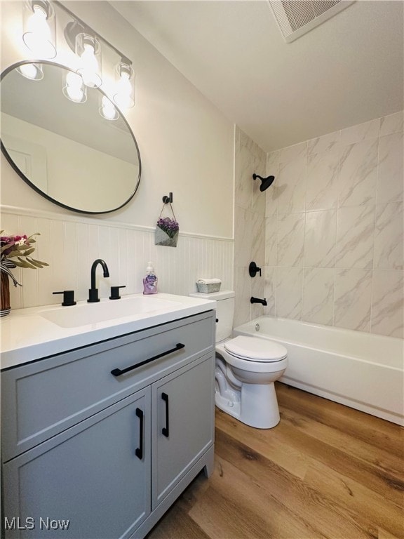 full bathroom with wood-type flooring, tiled shower / bath, vanity, and toilet