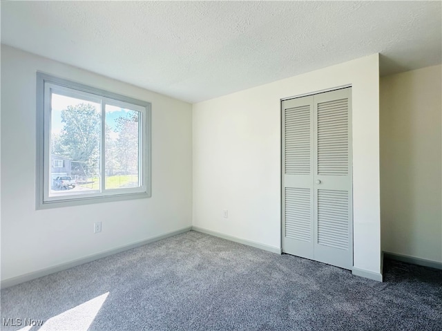 unfurnished bedroom with a textured ceiling, carpet flooring, and a closet