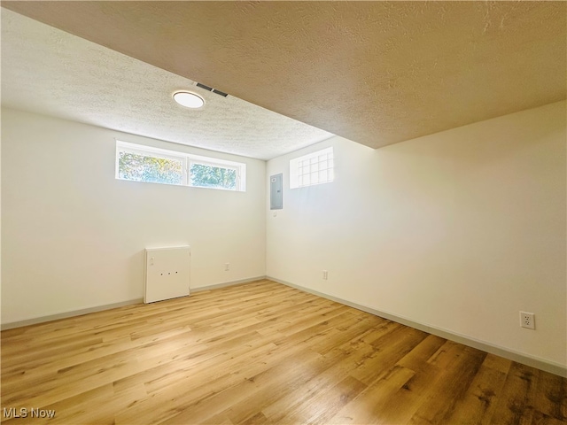 interior space featuring a textured ceiling, light hardwood / wood-style floors, and electric panel