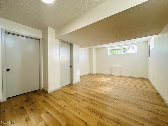 interior space with a textured ceiling and light hardwood / wood-style flooring