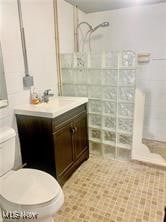 bathroom featuring vanity, toilet, and a tile shower