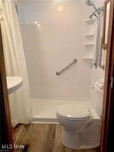 bathroom featuring walk in shower, hardwood / wood-style floors, and toilet