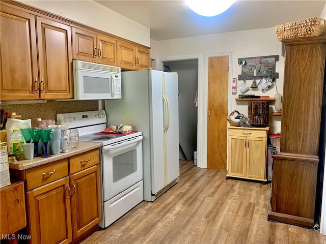 kitchen with light hardwood / wood-style floors, backsplash, and white appliances