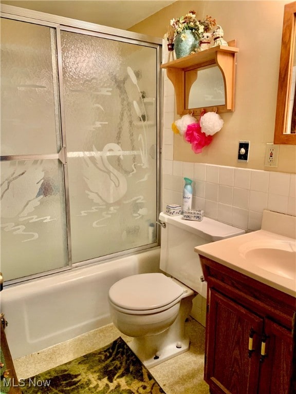 full bathroom featuring tile walls, combined bath / shower with glass door, vanity, and toilet