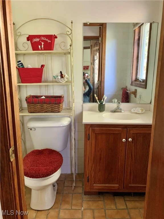 bathroom with tile walls, tile patterned floors, vanity, and toilet