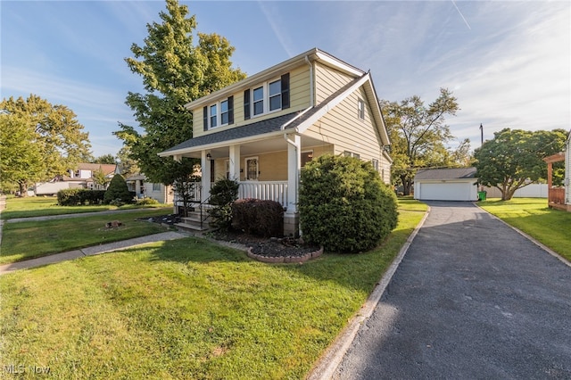 view of front of house featuring a front yard, a garage, a porch, and an outbuilding