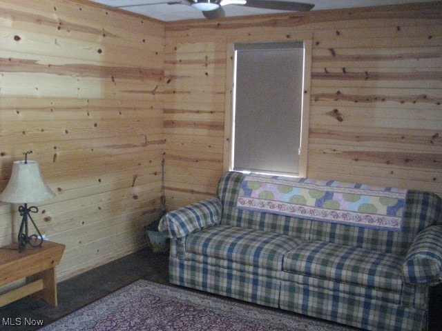 sitting room with wood walls and ceiling fan