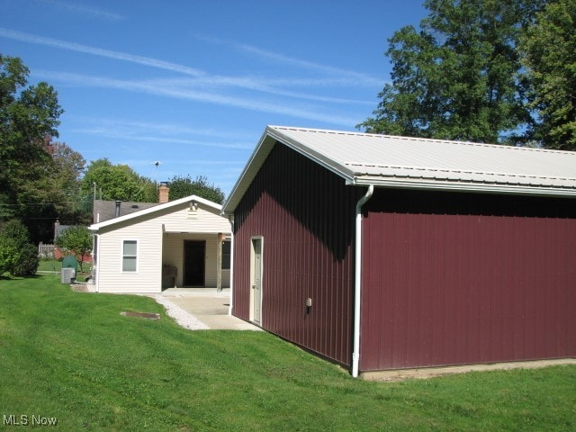 back of property featuring a lawn and an outbuilding