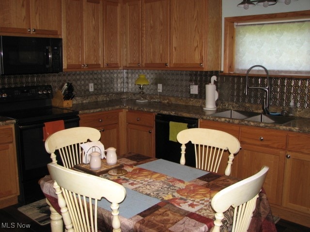 kitchen with dark stone counters, backsplash, sink, and black appliances