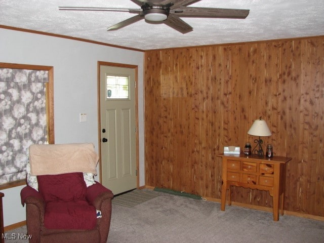 carpeted entryway with a textured ceiling, crown molding, and ceiling fan