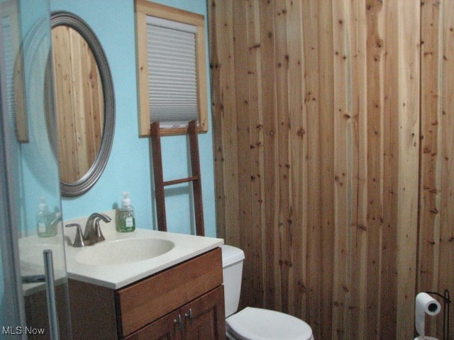 bathroom with wooden walls, vanity, and toilet