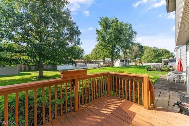 deck with a patio area, a yard, and a storage shed