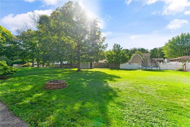 view of yard with a fire pit and a trampoline