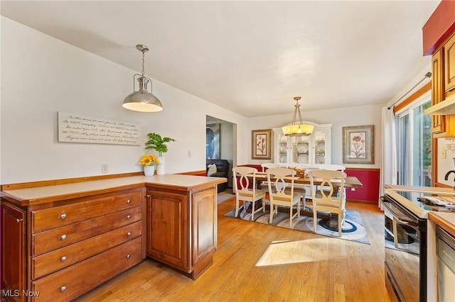 kitchen featuring pendant lighting, stainless steel range with electric stovetop, and light hardwood / wood-style floors