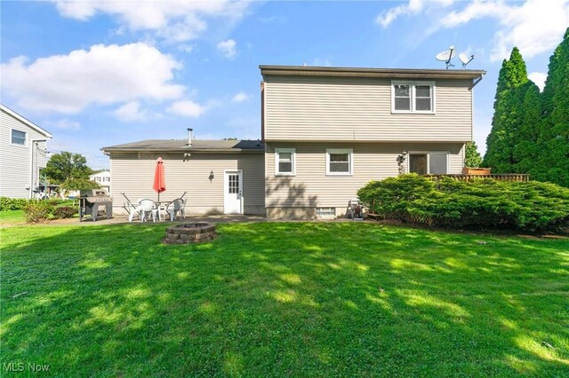 rear view of house with a fire pit, a patio area, and a yard