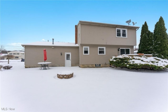 snow covered back of property featuring an outdoor fire pit